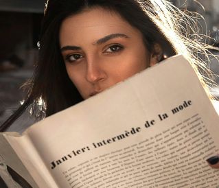 A woman enjoys a fashion magazine under warm sunlight, evoking a sense of style and relaxation.